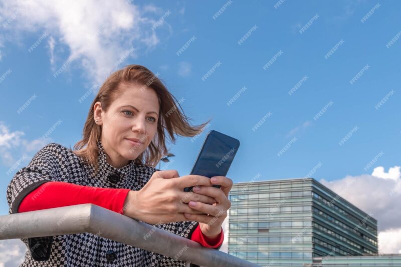 Young woman using mobile phone against sky